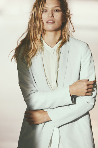 Elegant portrait of an adult woman in a black dress with natural makeup, posing against a textured backdrop in a photo studio setting.