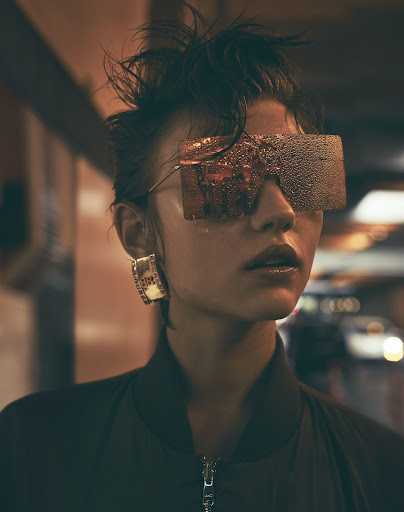 Close-up portrait of a woman wearing oversized reflective sunglasses and a dark zipped jacket, photographed by Stefano Galuzzi.