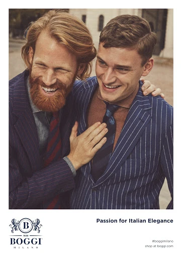 Two smiling men in pinstripe suits embrace outdoors, showcasing Italian elegance and fashion. A Boggi Milano ad with a warm, joyful mood.