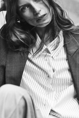 Close-up portrait of a woman in a striped button-up shirt and dark blazer photographed by Stefano Galuzzi