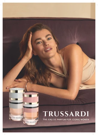 Woman leaning on a plush velvet sofa next to two perfume bottles for a Trussardi fragrance campaign by Stefano Galuzzi.