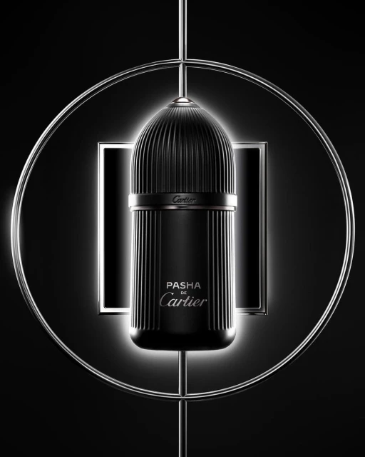 Elegant close-up of a black Pasha de Cartier fragrance bottle with fluted texture, highlighted by a circular metal frame against a dark backdrop.