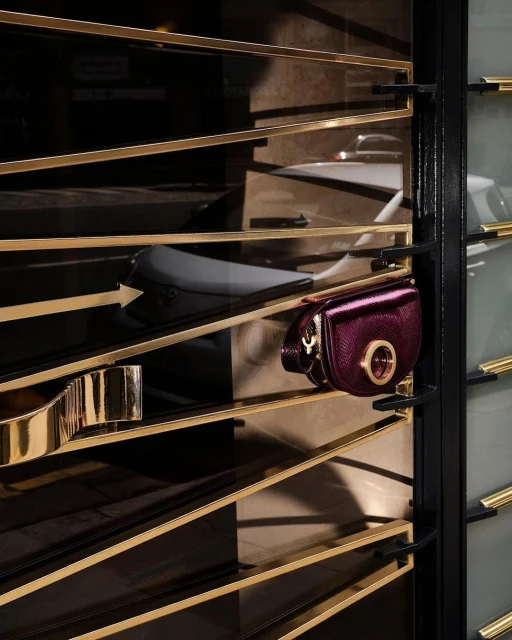 A close-up shot of a purple crossbody bag hanging on a gold metal display rack, creating an elegant and sophisticated fashion display.