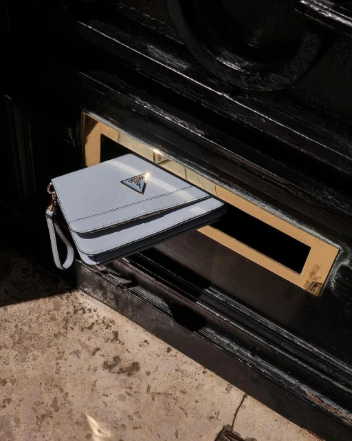 Close-up of a light blue purse with a gold logo in a dark setting, creating a luxurious feel with contrasting colors.