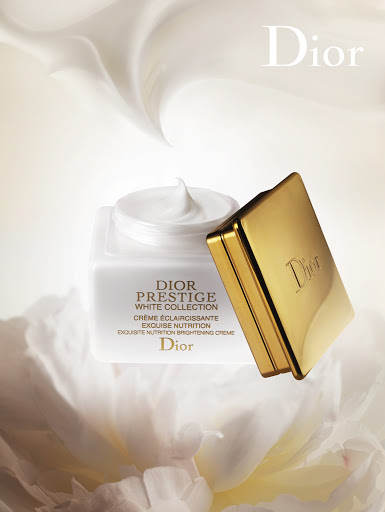 Dior Prestige White Collection creme jar with gold lid. The cosmetic product is showcased against a creamy white floral background.