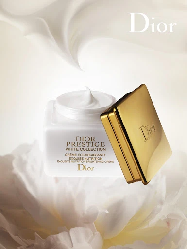 Dior Prestige White Collection creme jar with gold lid. The cosmetic product is showcased against a creamy white floral background.