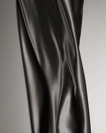 Black leather textile swatch with draping folds and texture detail under studio lighting, neutral grey background, product shot, high detail.