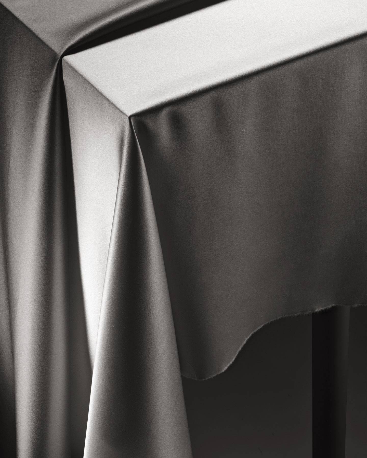 Elegant grey draped fabric over a table, creating soft folds and subtle lighting, ideal for background or design element.