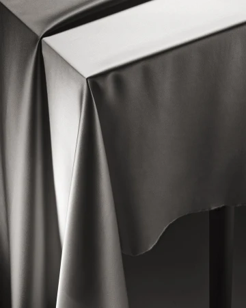 Elegant grey draped fabric over a table, creating soft folds and subtle lighting, ideal for background or design element.