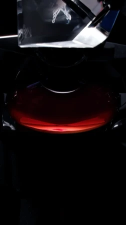 Low angle, close-up studio shot features a round, clear container filled with a dark red liquid with a clear rectangular object above it.