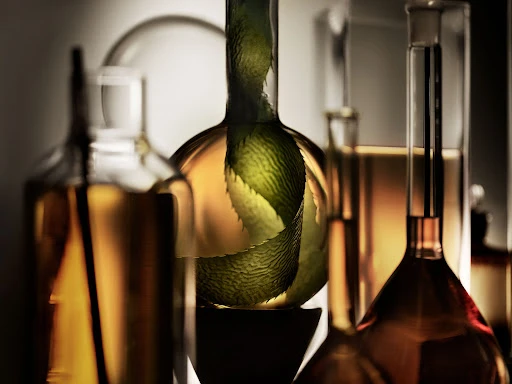 Glass laboratory beakers and flasks of various sizes and shapes containing clear and amber-colored liquid are arranged closely together.