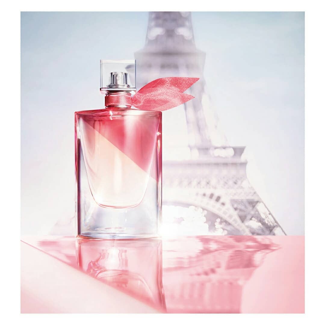 Elegant perfume bottle with a pink ribbon against the Eiffel Tower, creating a luxurious and romantic beauty image.