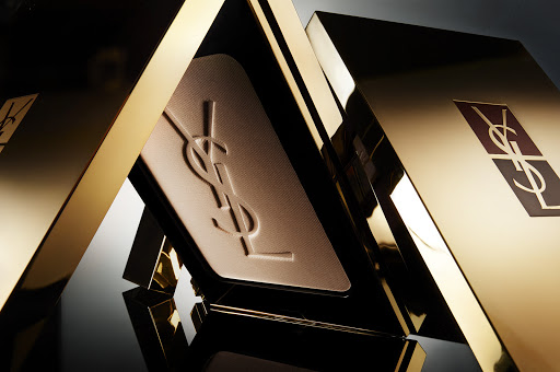 Close-up of luxurious gold YSL beauty compact case. High-end design, makeup product, and cosmetics. Elegant packaging and branding. Beauty aesthetic.