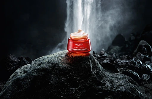 Vichy LiftActiv Collagen Specialist cream jar sits on a rock formation with a waterfall cascading in the blurred background.
