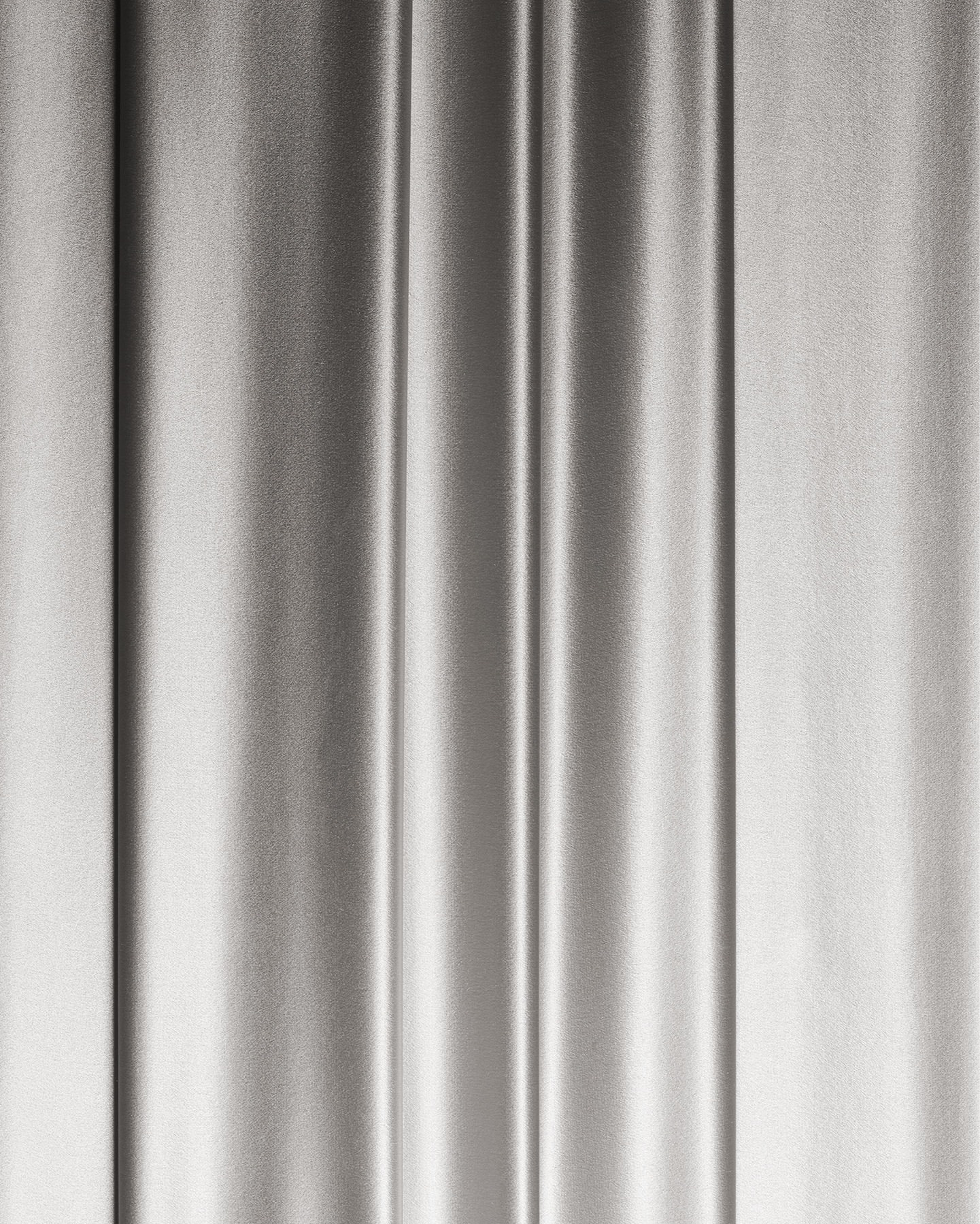 Elegant silver satin fabric drapes vertically with soft folds and subtle sheen, perfect for backdrops and luxurious textures.