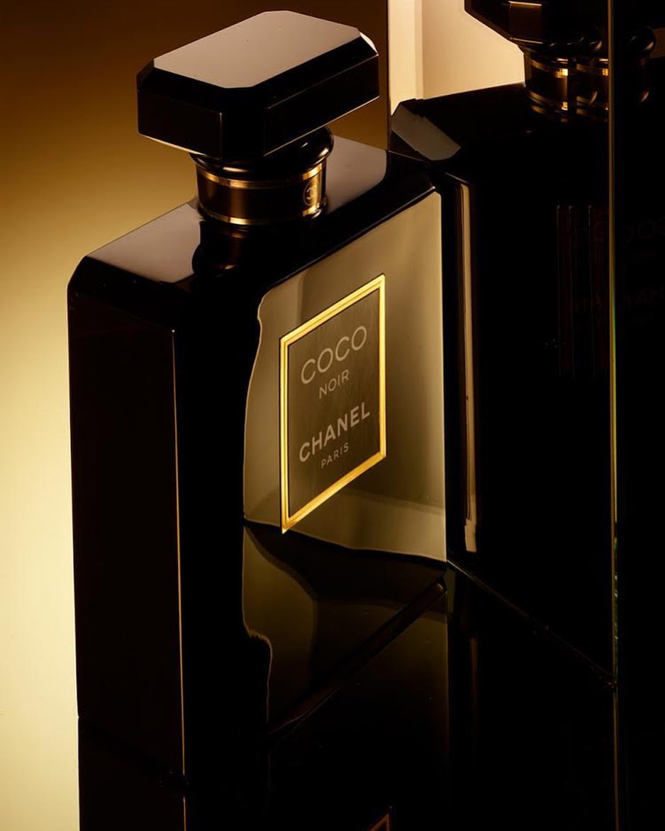 Close-up studio shot of two elegant, glossy black perfume bottles with gold accents, showcasing a luxurious and sophisticated fragrance.