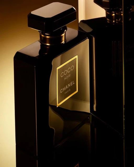 Close-up studio shot of two elegant, glossy black perfume bottles with gold accents, showcasing a luxurious and sophisticated fragrance.