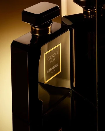 Close-up studio shot of two elegant, glossy black perfume bottles with gold accents, showcasing a luxurious and sophisticated fragrance.