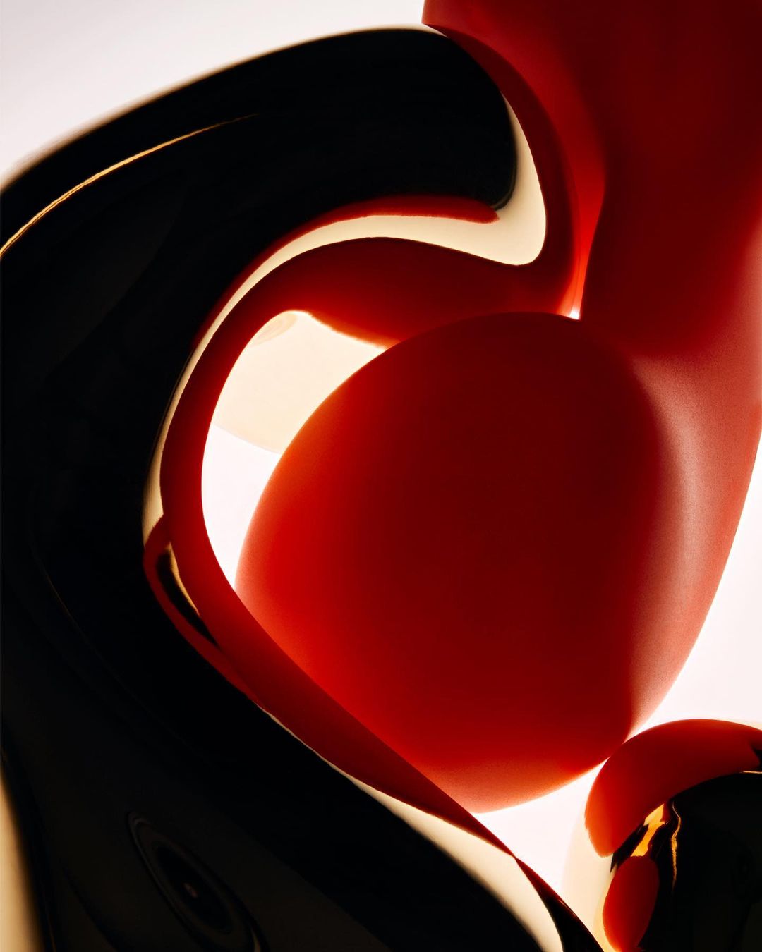 Abstract, flowing red and black forms create a dynamic composition against a bright white background, emphasizing smooth textures and fluid shapes.