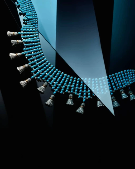 Necklace with turquoise beads and tassel details on a gradient blue to black background in a studio product shot for jewelry design.