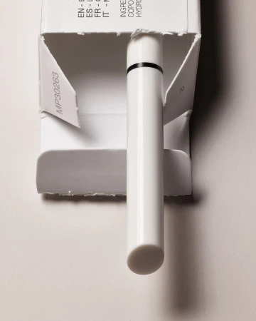 Close-up of a white eyeliner pen in an open white box on a white background. Beauty product, makeup application, simple composition.