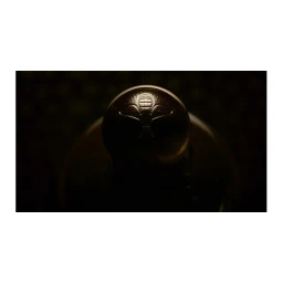 Close-up macro shot of a metallic sphere with an intricate engraved crest under warm, low-key lighting.