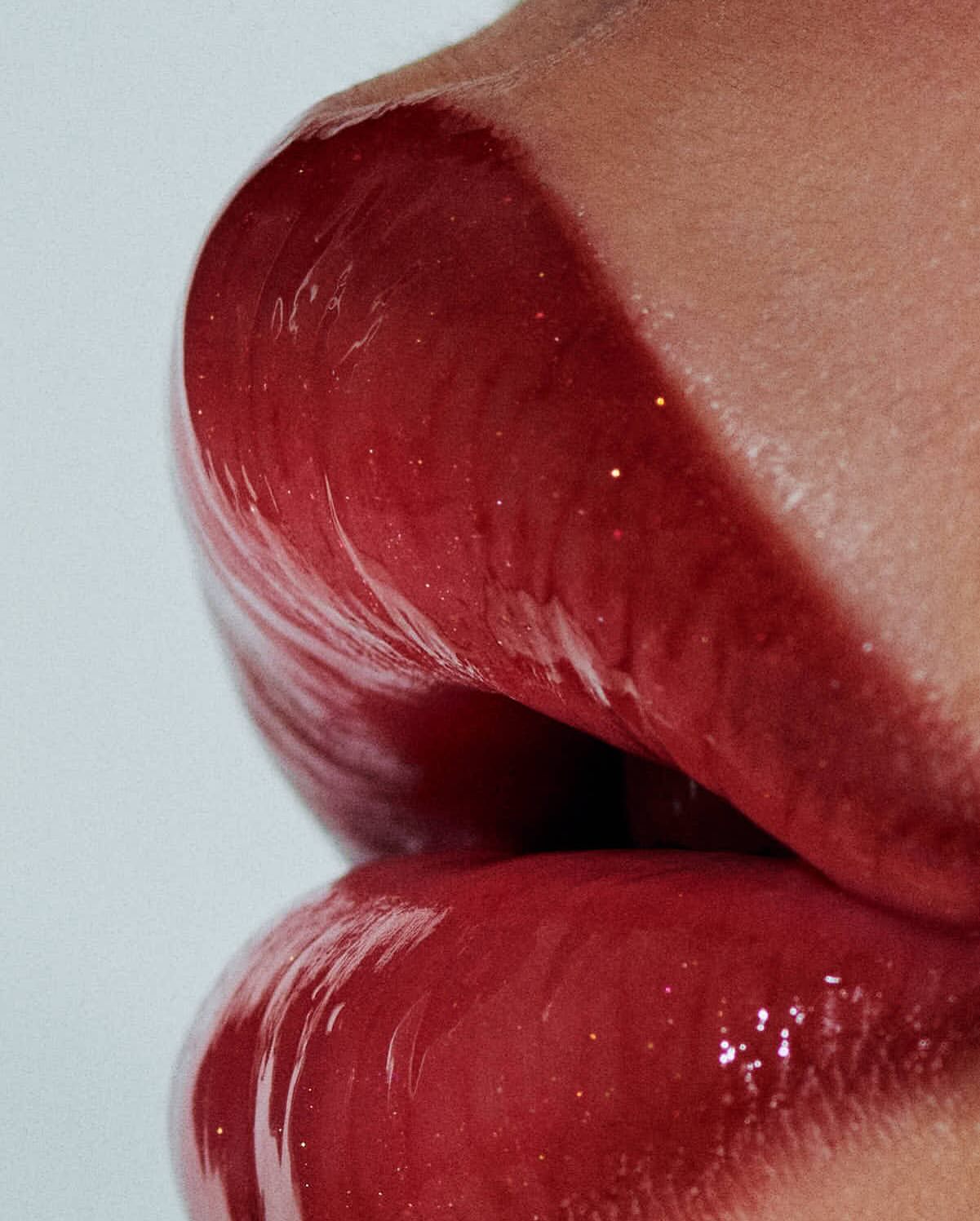 Close-up of an adult female's face featuring glossy red lips. The person's skin is visible on the upper portion of the image.