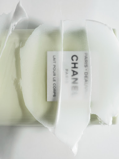 Close-up of Chanel body lotion showing its creamy texture and brand label in a studio setting against a bright white background.