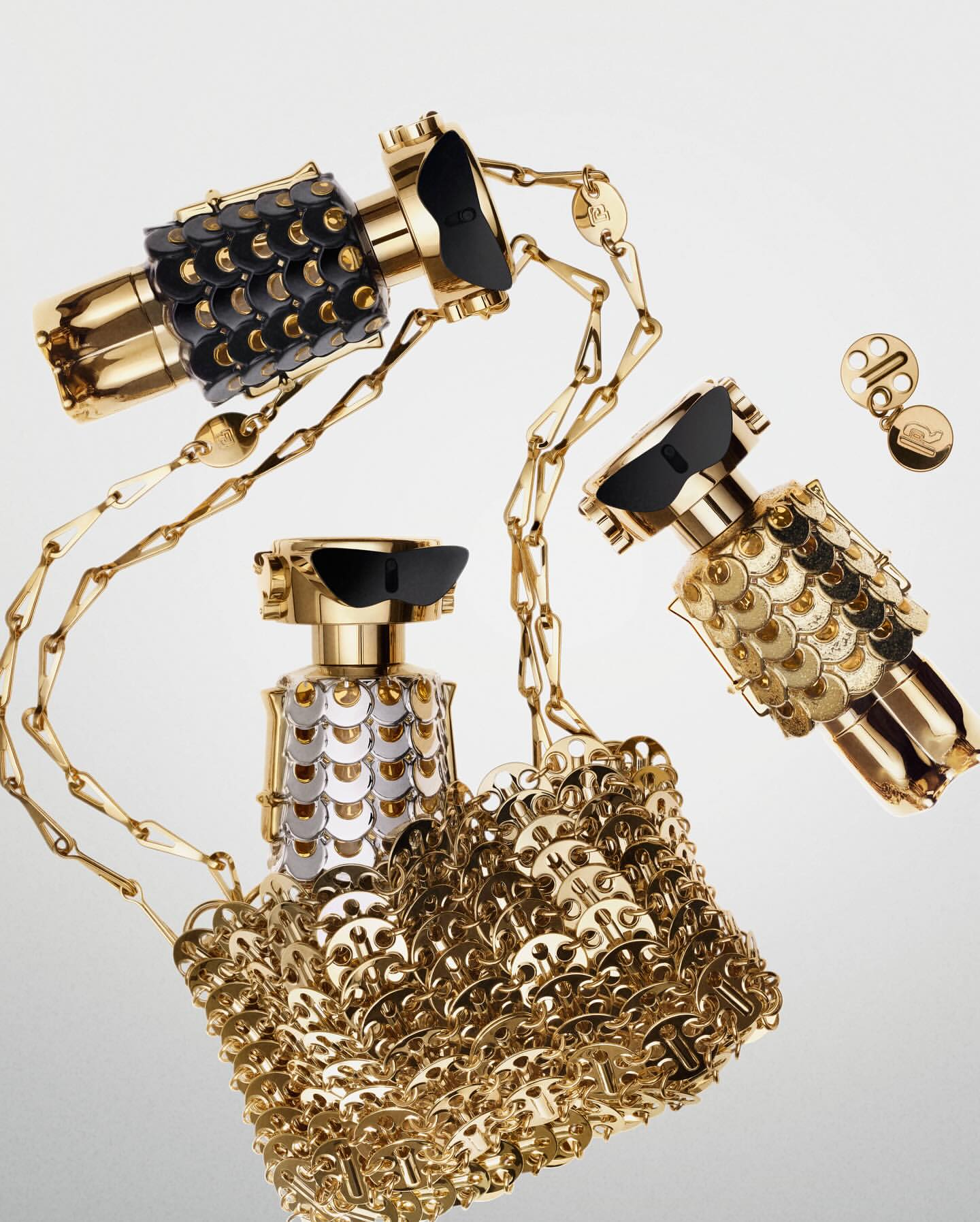 Three gold perfume bottles with decorative details, linked together with a gold chain, are displayed on a white gradient background.