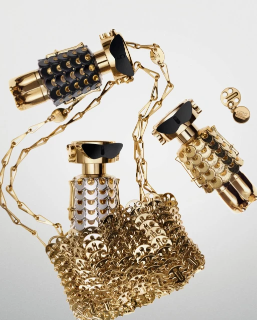 Three gold perfume bottles with decorative details, linked together with a gold chain, are displayed on a white gradient background.