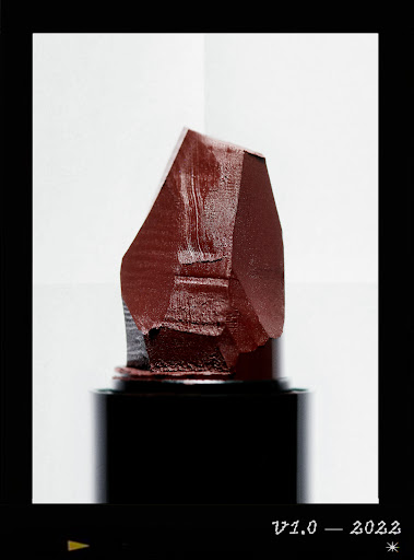 Close-up of dark red lipstick bullet against a gradient white background, showcasing beauty product photography.