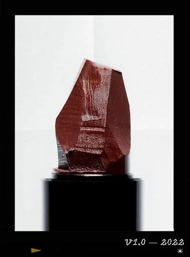 Close-up of dark red lipstick bullet against a gradient white background, showcasing beauty product photography.