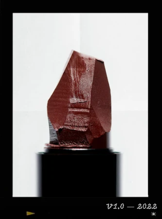 Close-up of dark red lipstick bullet against a gradient white background, showcasing beauty product photography.