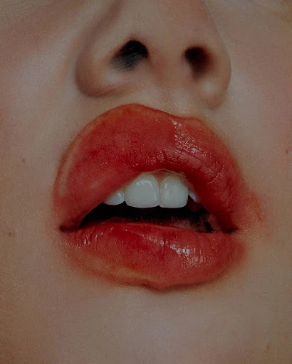 Close-up shot of an adult female with red lipstick, open mouth, visible teeth, and nose. Beauty and fashion concept in a macro view.