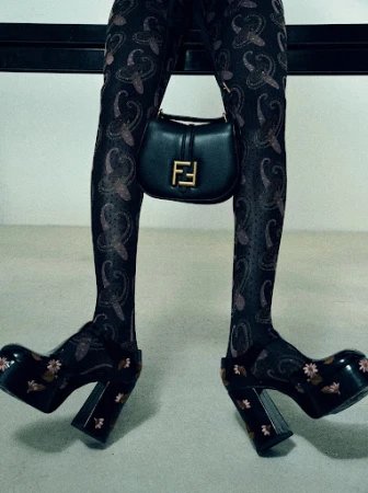 Person wearing patterned tights and platform heels, holding a black Fendi handbag. Fashionable legwear and accessory. 