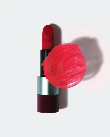 Still life studio shot of a red Hermes lipstick with a smear of red lipstick on a clean white surface. Beauty product photography.