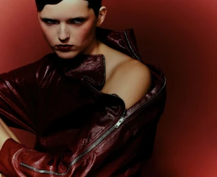 Model in a dark red leather zip jacket against a deep red gradient background photographed by Zoé Kovacs