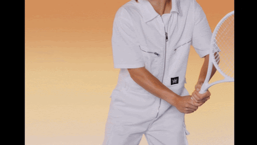 A person in a white jumpsuit holds a tennis racket against an orange gradient background, showcasing activewear fashion.