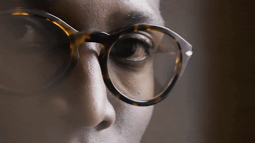 Close-up of a person's face wearing tortoiseshell eyeglasses, capturing the detail of the eyewear and the skin's texture.