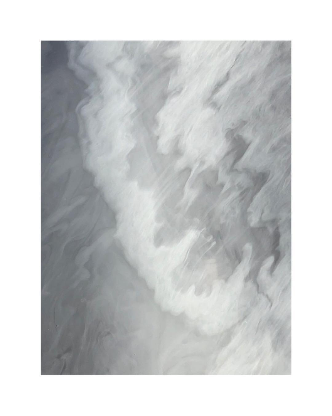 Abstract swirling patterns in shades of gray and white create a dynamic and textured visual effect.