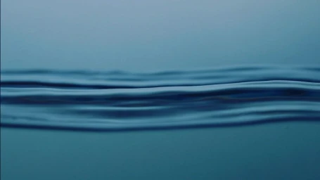 Close-up abstract view of smooth, dark blue water ripples forming horizontal lines