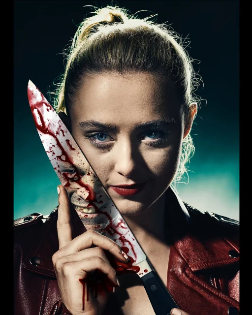 Blonde woman in red leather jacket holds blood-covered knife, smiling in a portrait shot with dark lighting, close-up view.