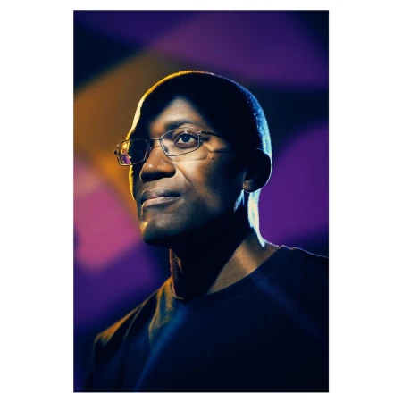 Portrait of a Black man wearing glasses with dramatic side lighting and a purple background by F. Scott Schafer