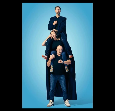 Three people stacked in a human pyramid against a bright blue gradient backdrop photographed by F. Scott Schafer.