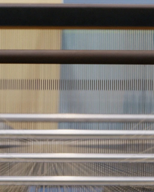 Abstract image featuring parallel vertical lines in beige and blue hues, overlaid with horizontal metal rods creating a structured pattern.