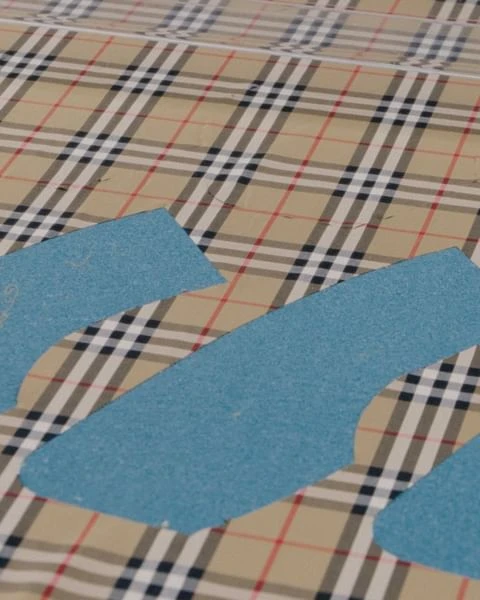 Beige plaid fabric with blue paper patterns, flat lay. Abstract sewing or textile design concept.
