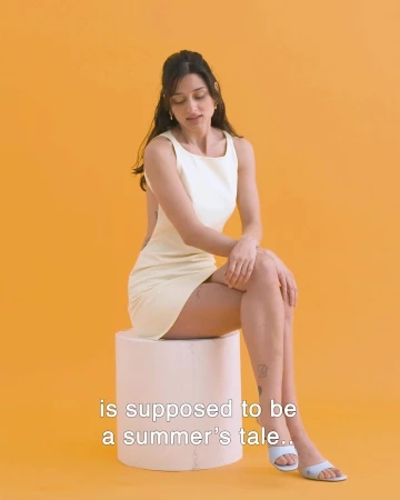 Woman in pale yellow dress seated on cylindrical pedestal against yellow background by Michele Foti