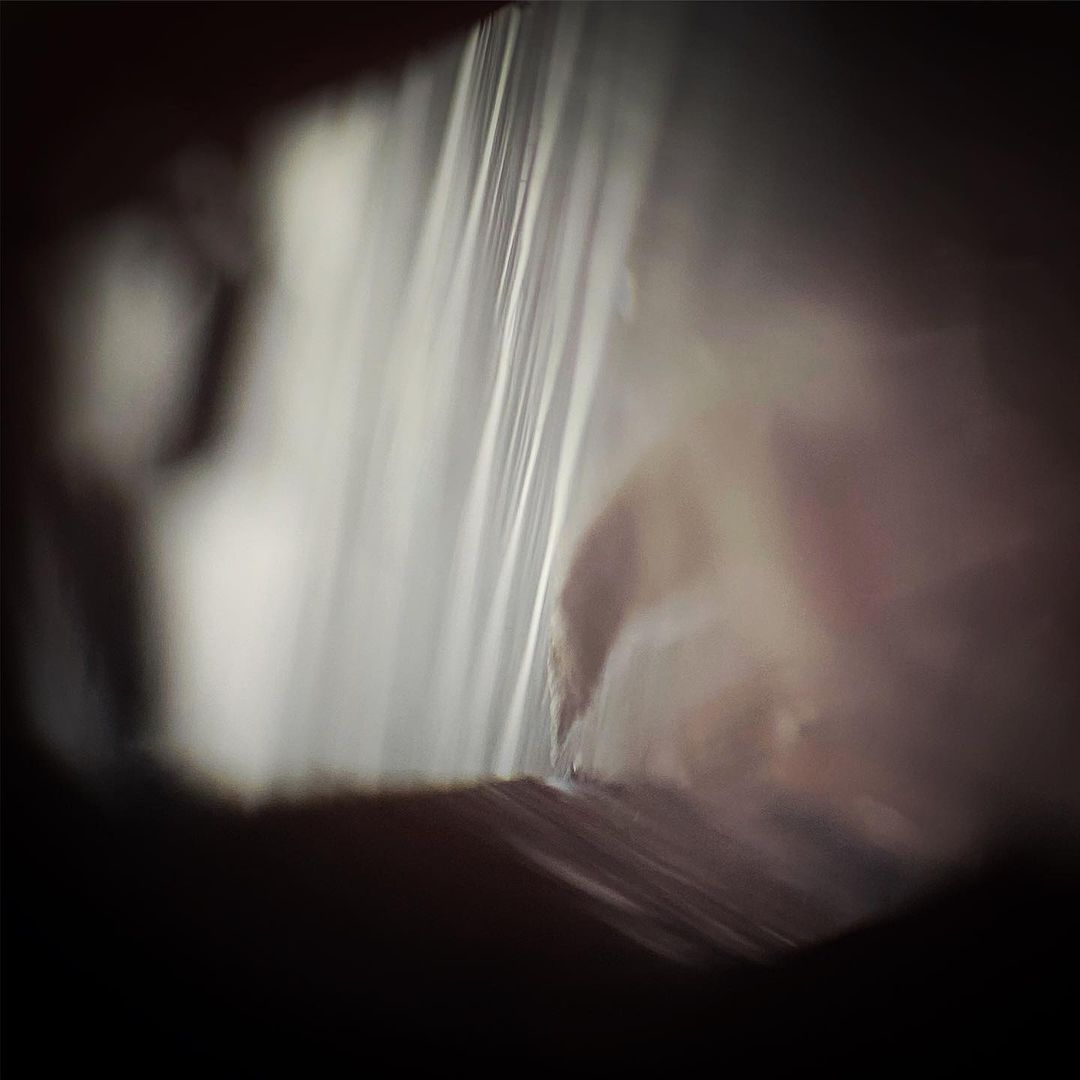 Abstract macro photograph showing blurred light refracting through a transparent plastic material with dark surroundings, close up view.
