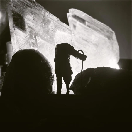 Silhouette of a person with a cane standing between two dark rocks, with a large crystal formation in the background.