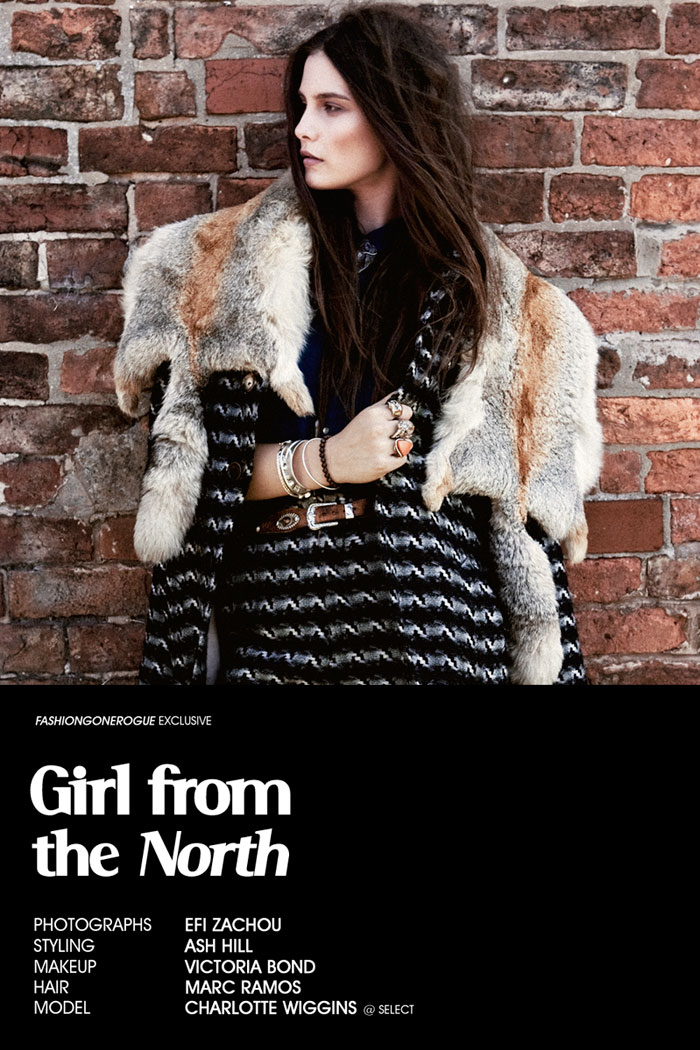 Fashion editorial shot of a brunette adult woman with a fur stole in front of a brick wall, wearing a patterned knit dress with a belt.